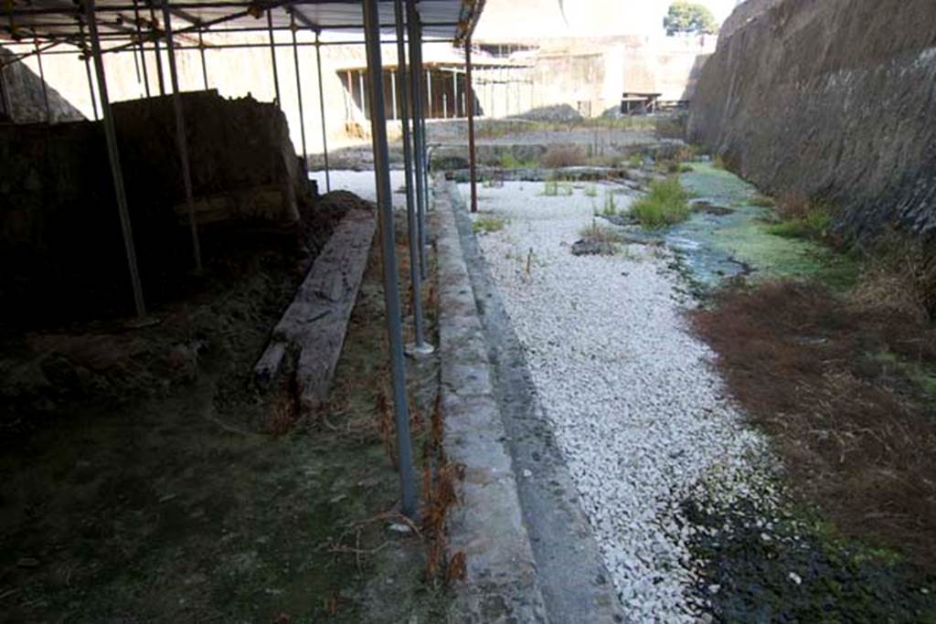 Villa dei Papiri, Herculaneum. July 2010.
Looking east along part of the monumental structure/hall, on left, with area of pool, on right. Photo courtesy of Michael Binns.